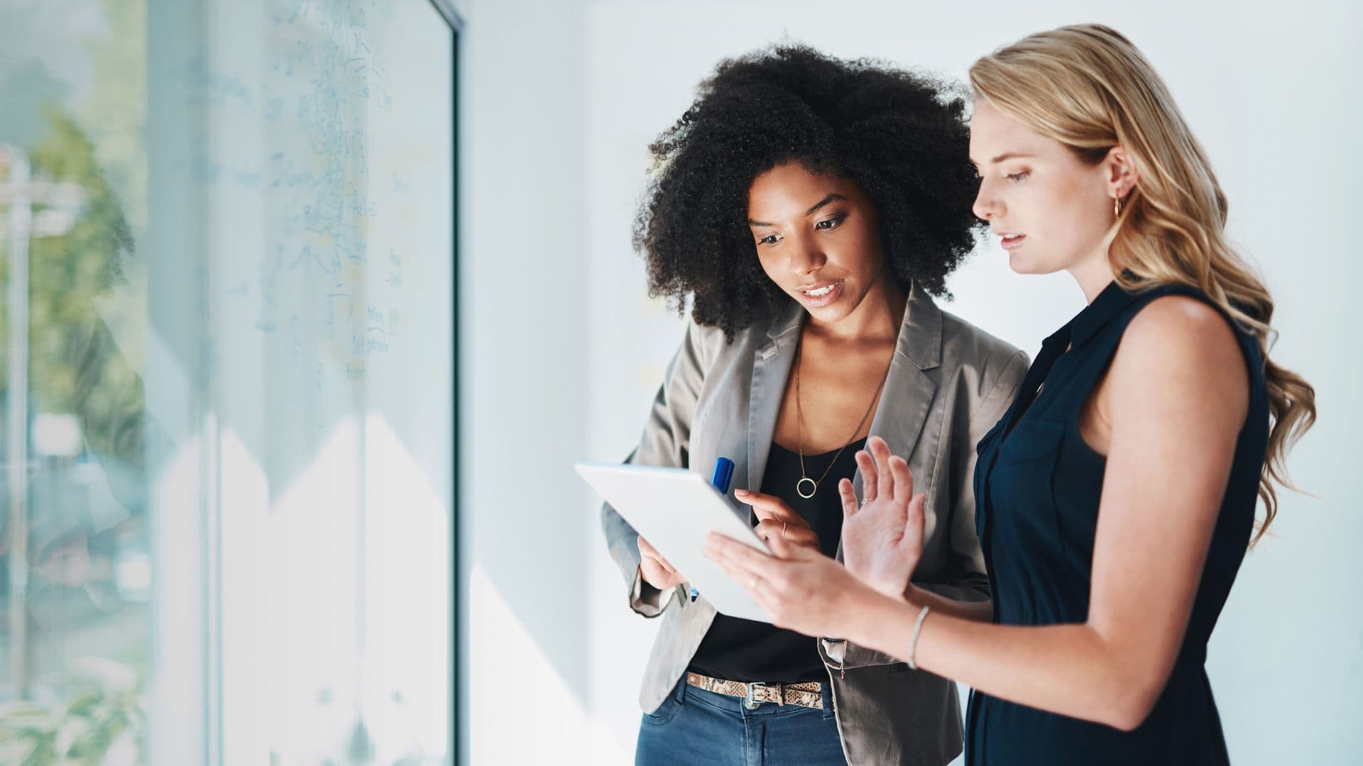 Two women working on a tablet, representing how marketers use Amplitude